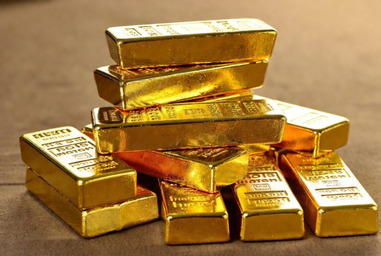 Pile of shiny gold bars stacked on a brown surface